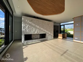 Sala de estar com parede de pedra e piso claro em um imóvel no Brasil.
