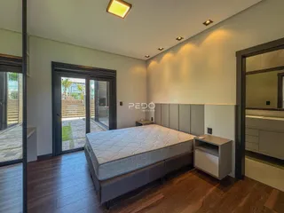 Quarto com piso de madeira e porta de vidro abrindo para o exterior.