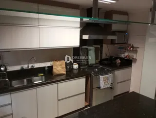 Interior de uma cozinha moderna com armários brancos e bancadas escuras.