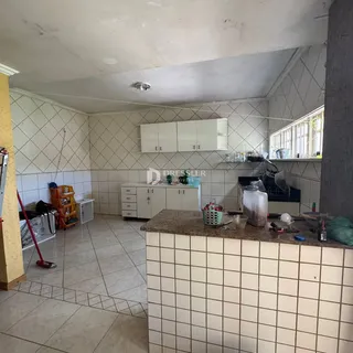Interior da cozinha com revestimento de azulejos brancos e armários brancos.