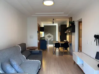 Interior de uma sala de estar com piso de madeira clara e ambiente moderno.