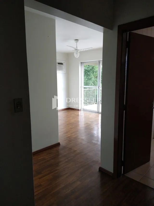 Vista de um corredor interno com piso de madeira e porta de entrada para uma área externa.
