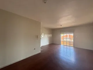 Ambiente interno de uma sala ampla com piso de madeira escura.