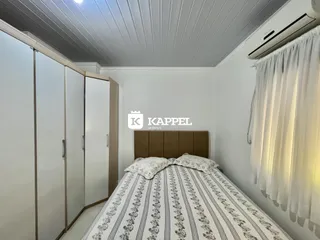 Quarto com cama e armários brancos em um imóvel.