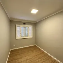 Foto de um corredor interno com piso de madeira e janela.