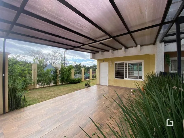 Vista da fachada de uma residência com piso de madeira e área externa coberta.