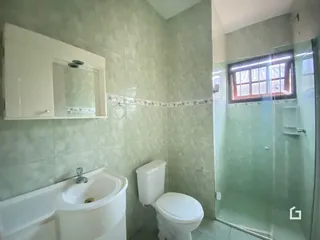 Foto de um banheiro com revestimento de azulejos claros e box de vidro.