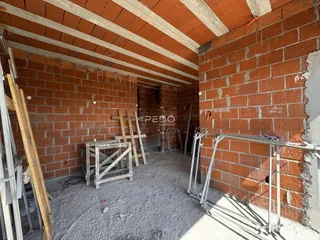 Interior de uma sala em construção com paredes de tijolo aparente.