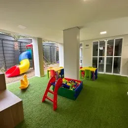 Ambiente interno com carpete verde e móveis coloridos em uma área comum.