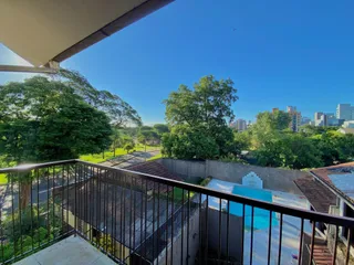 Vista da varanda mostrando árvores e uma piscina no telhado.