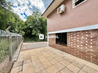 Fachada de casa com alvenaria de tijolos aparentes e pátio pavimentado.