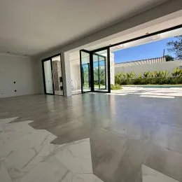 Sala ampla com piso de mármore e portas de vidro que dão acesso ao exterior.