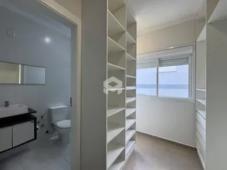 Interior de um corredor com acesso a um banheiro e um armário de parede branco.