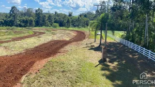 Uma paisagem de campo com trilha de terra e cerca branca.