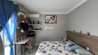 Quarto com cabeceira de madeira e janela com cortinas azuis.