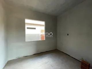 Uma sala vazia com paredes brancas e piso de concreto.
