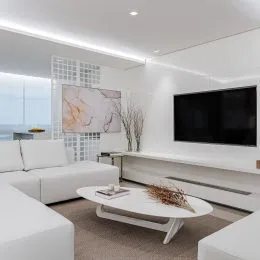 Uma sala de estar moderna com sofá branco e televisão na parede.