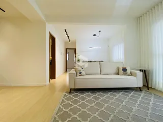 Sala de estar com sofá branco e piso de madeira clara.