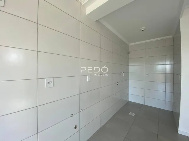 Vista interna de um corredor com paredes brancas e piso cinza.