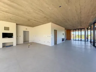 Espaço interno amplo com teto de concreto aparente e paredes brancas.
