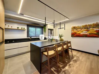 Cozinha moderna com armários brancos e ilha escura.