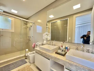 Banheiro moderno com bancada de mármore e box de vidro.