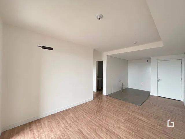 Ambiente interno com piso de madeira clara e paredes brancas.