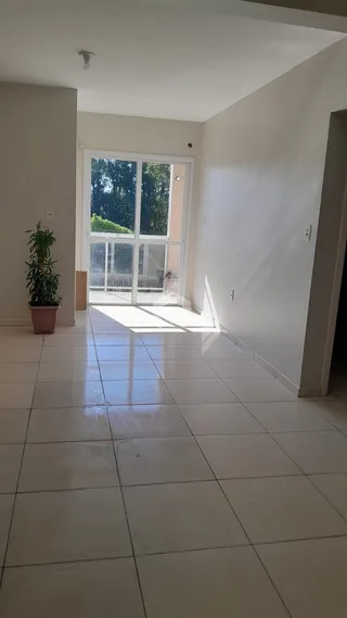 Interior de uma sala com piso de cerâmica e porta de vidro.