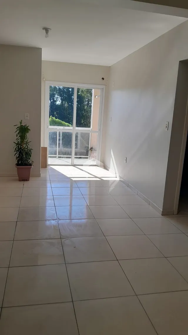 Interior de uma sala com piso de cerâmica e porta de vidro.