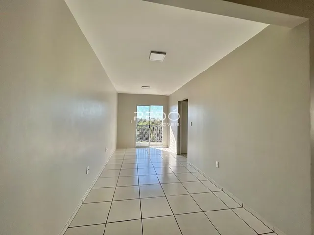 Corredor interno de uma residência com piso de cerâmica branca.
