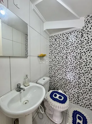 Banheiro com revestimento de azulejos pretos e brancos e pia branca.