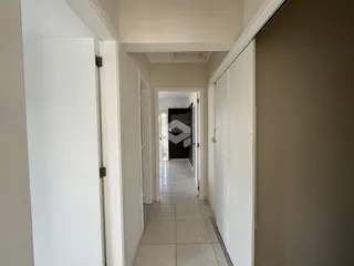 Corredor interno de uma residência com paredes brancas e piso de cerâmica.