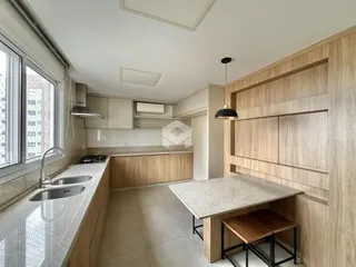 Vista da cozinha com armários de madeira clara e bancadas claras.