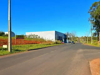 Vista externa de uma propriedade com uma rua asfaltada e vegetação ao fundo.