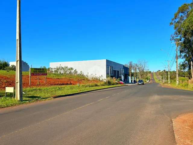 Vista externa de uma propriedade com uma rua asfaltada e vegetação ao fundo.