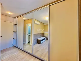 Hall com piso de madeira e portas espelhadas em um imóvel.