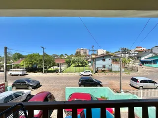 Vista externa de uma rua residencial em Lajeado, Brasil, com casas e veículos estacionados.