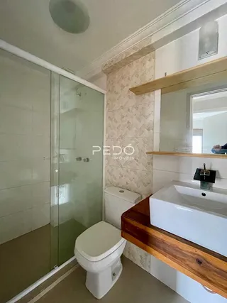 Foto de um banheiro com revestimento de cerâmica e box de vidro.