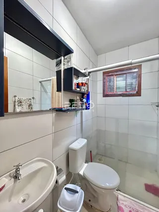 Foto de um banheiro com azulejos brancos e louças sanitárias.