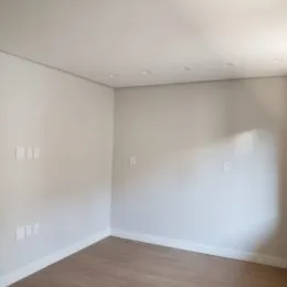 Ambiente interno com paredes brancas e piso de madeira clara.