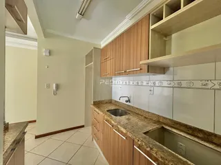 Vista interna de uma cozinha com armários de madeira e bancada de granito.