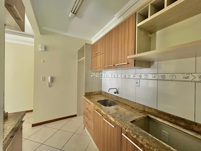 Vista interna de uma cozinha com armários de madeira e bancada de granito.