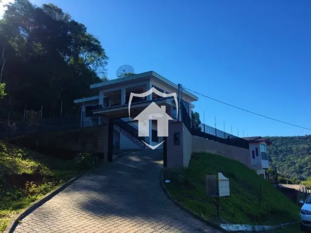 Fachada de uma residência em Lajeado, Brasil, com terreno inclinado.