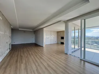 Sala ampla com piso de madeira e grandes janelas de vidro.