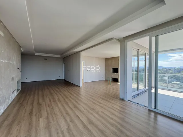 Sala ampla com piso de madeira e grandes janelas de vidro.