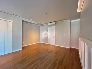 Ambiente interno de uma sala ampla com piso de madeira.