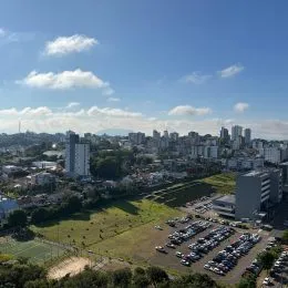 Vista de uma área verde com edifícios urbanos ao fundo.