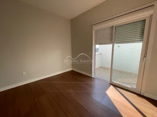 Ambiente interno com piso de madeira e porta de vidro que dá acesso a outro espaço.