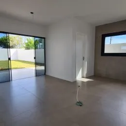 Ambiente interno amplo com piso claro e portas de vidro que dão acesso a um jardim.