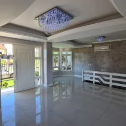 Sala de estar ampla com piso claro e iluminação central no teto.